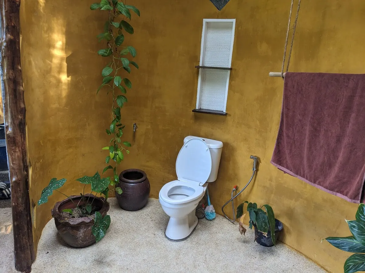 Earth-plastered open-air bathroom with plants and hot water