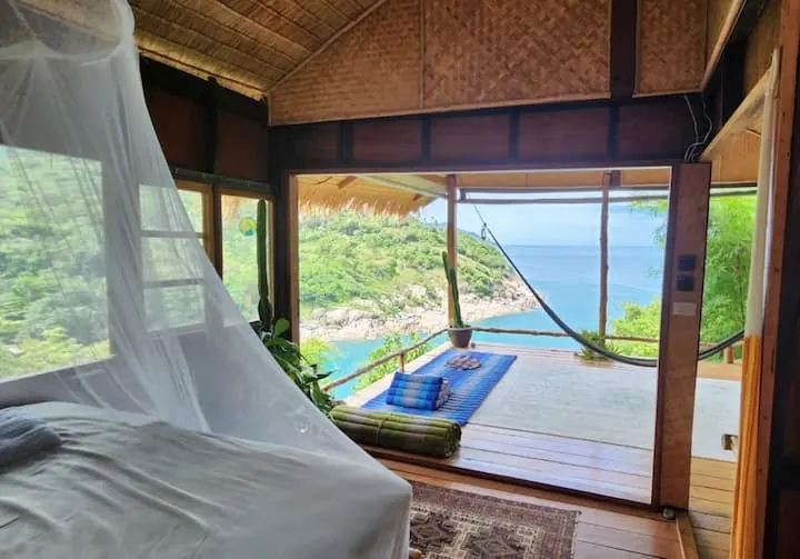 Bed with mosquito net opening onto the deck and sea view