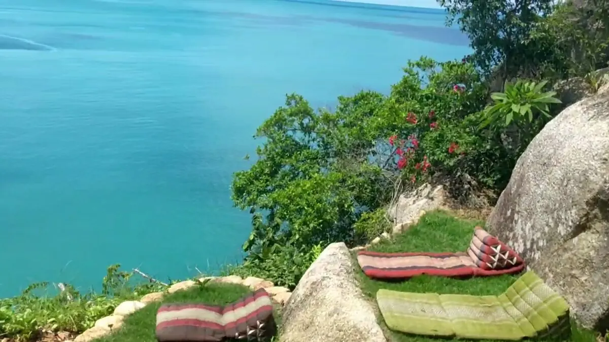 Floor cushions on a rock ledge with a turquoise ocean view