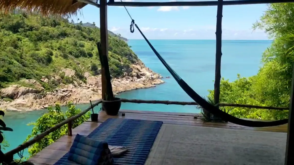 Wooden deck of the Why Nam villa with a hammock, looking out over the turquoise bay on Koh Phangan