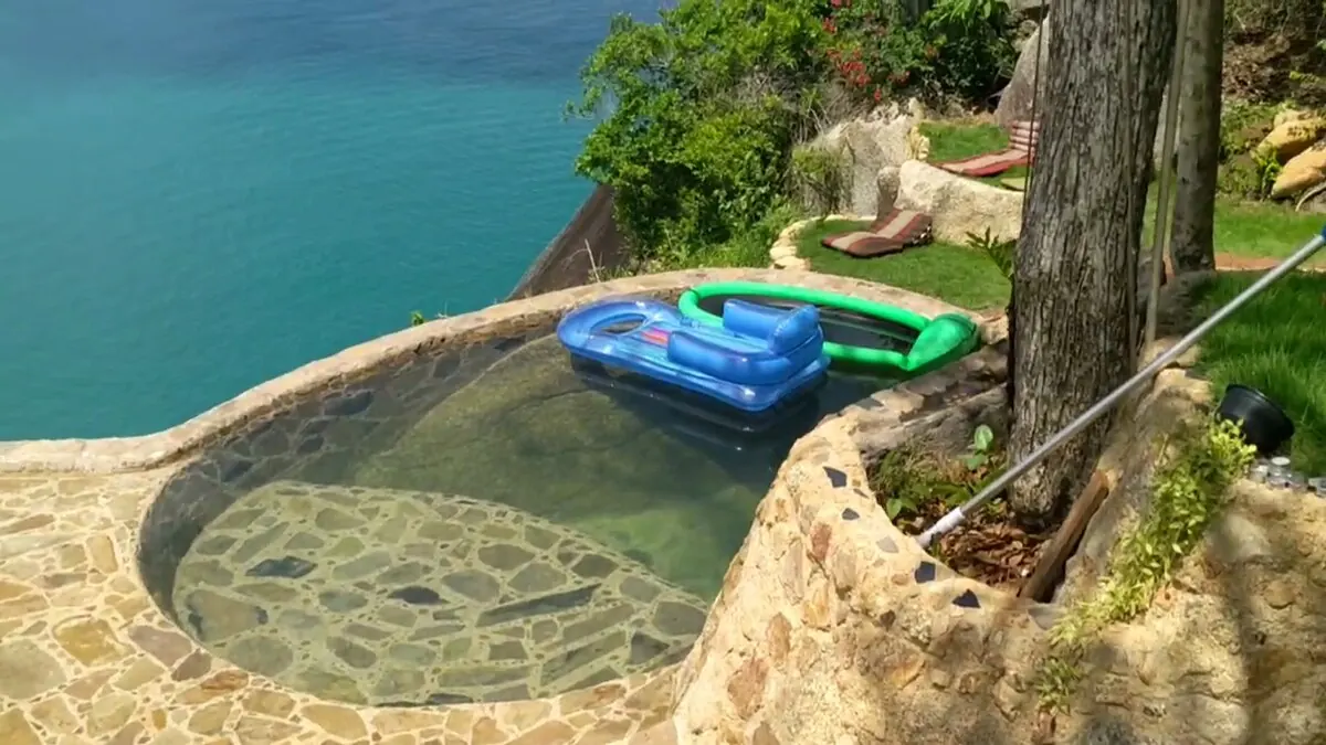 Stone-lined private pool with ocean view beside the villa lawn